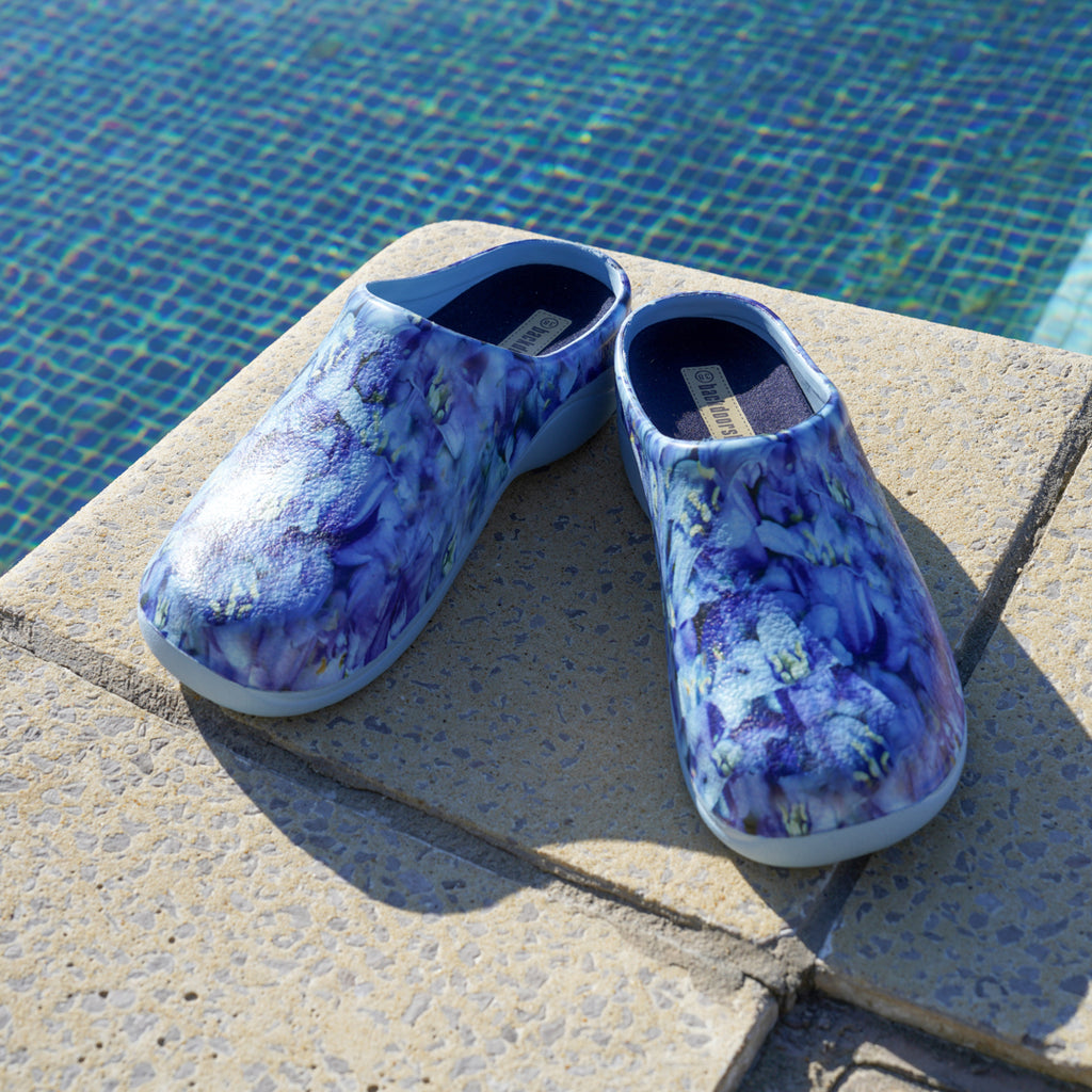 image of blue bell floral clogs next to a swimming pool